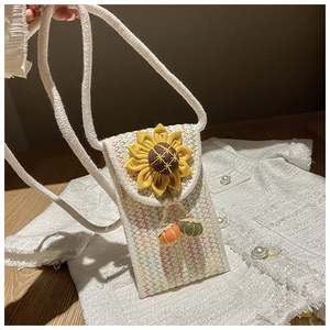 Detail of woven straw phone bag featuring a large sunflower and mini pumpkin pendants