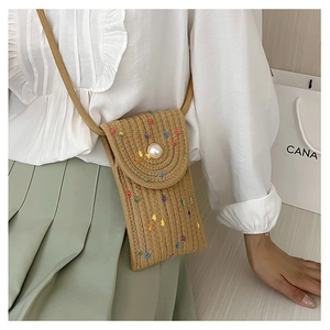 Detailed view of woven straw mini bag featuring colorful floral accents and a pearl buckle