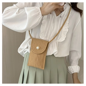 Close-up of woven straw mini bag with a pearl button closure and slim shoulder strap