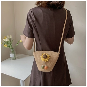 Detail of beige straw bucket bag with sunflower decor on a model in home setting