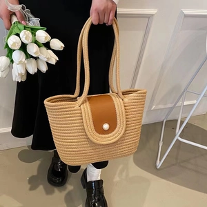 Handwoven straw tote bag with brown leather flap and pearl button for beach vacation