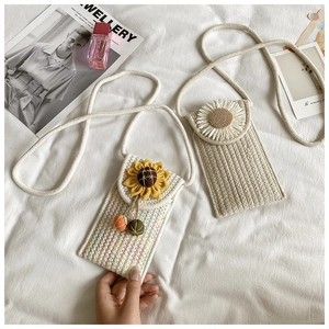 Detail showing hand-woven cotton phone bags with daisy and sunflower accents on fabric