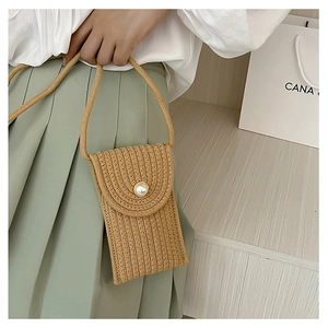 Detail of a straw mini phone bag with pearl button and long crossbody strap