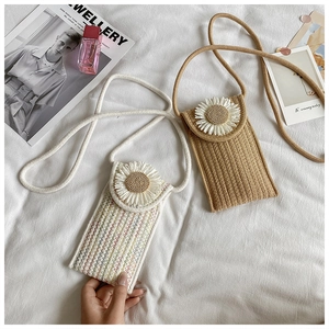 Detailed view of handmade woven straw mobile bags featuring large white daisy flower accents