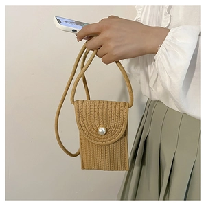 Detail of straw woven mini crossbody phone bag featuring a pearlescent button closure