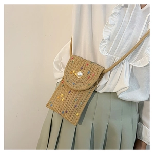 Detail of straw woven phone bag with colorful embroidery and a large pearl buckle