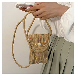 Close-up of straw mini crossbody bag with pearl buckle on a woman's casual outfit