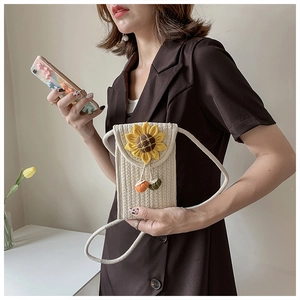 Detail of hand-woven beige cotton shoulder bag featuring a yellow sunflower and small charms