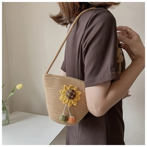 Detail of straw bucket bag featuring sunflower decor and colorful pendant charms