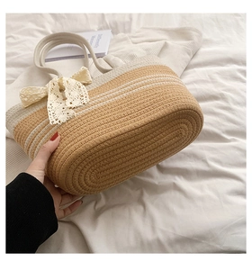 Détail d'un sac de plage tressé main avec nœud en dentelle et design bicolore en coton