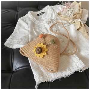 Detail of straw bucket bag with sunflower decor and colorful pompons on tweed fabric