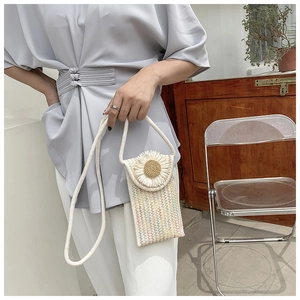 Close-up of woven straw cell phone bag with white daisy decor and rope strap