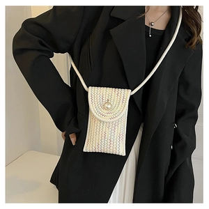 Detail of hand-woven mini straw phone bag with colorful wavy stitching and a pearl buckle