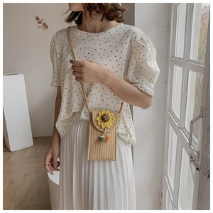 Close-up of woven straw shoulder bag with sunflower detail worn by a model