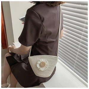 Detail of white straw bucket bag with 3D daisy flower worn on a brown outfit