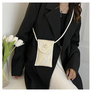 Detail of woven straw mini bag featuring wave pattern, pearl closure and white tulip