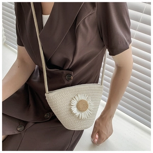 Detail of hand-woven crossbody straw bag with a 3D daisy flower and rope strap