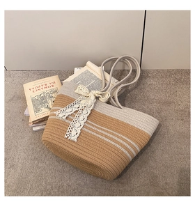 Détail du sac de plage en paille avec nœud en dentelle blanche et anses en corde
