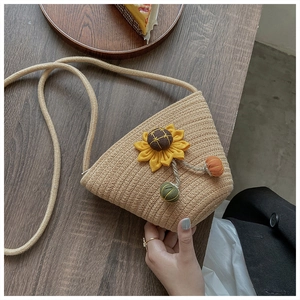 Detailed macro view of woven straw bucket bag with 3D sunflower decoration and mini pom-poms