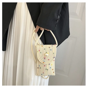 Detail of a mini straw woven phone bag featuring a pearl button and colorful accents