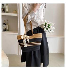 Détail du sac cabas en paille tressé avec élégant nœud en dentelle blanche et design bicolore