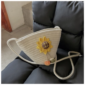 Detailed close-up of straw woven bucket bag with yellow sunflower and pumpkin charms