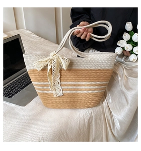 Détail du sac de plage tissé main avec nœud en dentelle et rayures blanches sur paille tressée