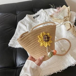 Detailed macro of khaki straw bucket bag with sunflower decor and colorful pompom charms