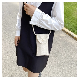 Detail of a beige woven mini phone bag featuring a large pearl button and vertical texture