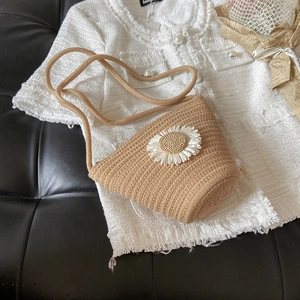 Detailed view of woven straw bucket bag with daisy flower on tweed jacket background