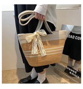 Détail d'un sac de plage tressé avec nœud en dentelle beige et motif rayé chic