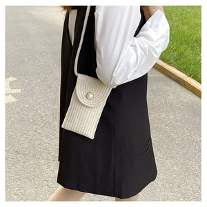 Detail of white woven mini crossbody bag featuring a large pearl button closure