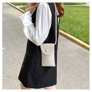 Detail view of woven straw mini bag with pearl button closure and knit texture