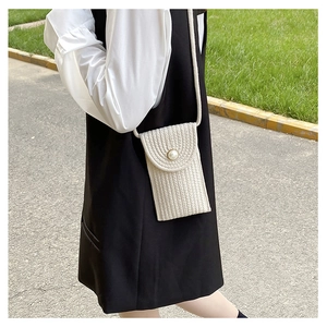 Detail of cream woven straw mini crossbody bag with a large pearl closure detail