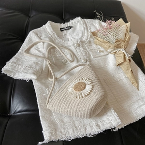 Detail of tweed top with pearl buttons and straw bucket bag with white daisy decor