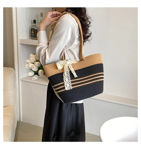 Détail du sac de plage tissé avec rayures sombres et nœud en dentelle blanche élégant