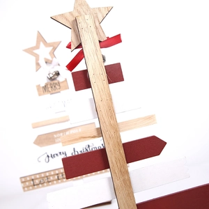 Detail of wooden Christmas tree sign with bells, ribbons and holiday text prints