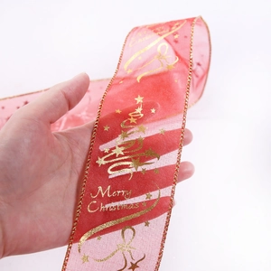 Close-up of red sheer Christmas ribbon with gold Merry Christmas lettering and stars