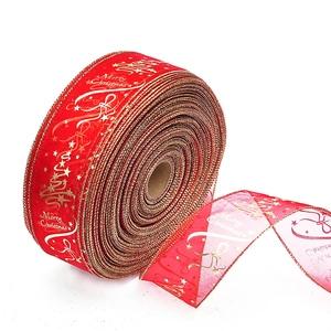 Detail of red Christmas ribbon roll with gold Merry Christmas print and festive tree motifs