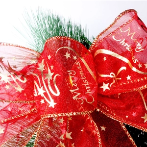 Macro detail of red organza Christmas bow with gold Merry Christmas print and wire edge
