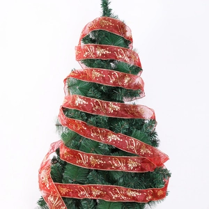 Detail of red sheer Christmas ribbon with gold glitter Merry Christmas prints on tree