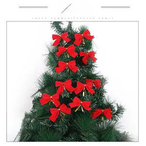 Detail of mini red velvet Christmas bows with gold ties hanging on a festive tree
