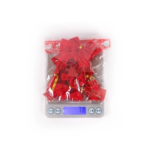 Macro shot of a set of shiny red Christmas bows with gold ties on a digital scale 7.8g