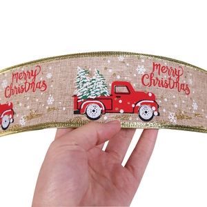 Close-up of Merry Christmas ribbon with red truck and gold trim for holiday decor