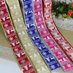 Close-up of decorative Christmas ribbons with snowflake and reindeer prints on burlap background