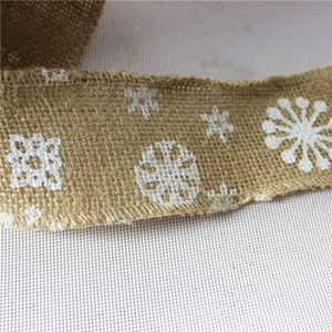 Close-up of natural jute ribbon with white snowflake patterns and stitched edges for decor