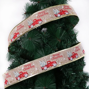 Detail of burlap Christmas ribbon with red truck print wrapped around green tree branches