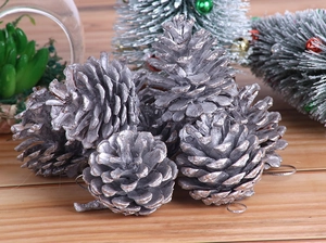 Close-up of silver-painted natural pine cones with hanging ropes for Christmas tree decor