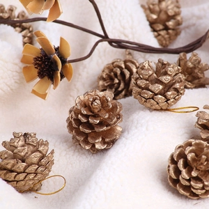 Close-up of gold-painted natural pine cones with hanging strings for Christmas decor