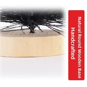 Detail showing the natural round wood base of a handmade mini black pine needle Christmas tree